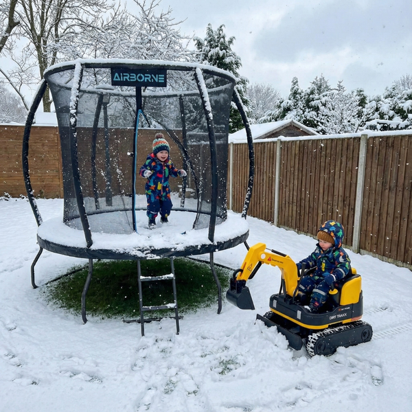 Kids playing outdoors with a trampoline and a kids digger