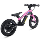 A pink and black balance bike with a suspension fork, black seat, and black wheels, shown from a three-quarters angle on a white background.