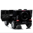 A black Mercedes-Benz AMG ride-on toy truck styled like a G-Class vehicle, shown from a rear three-quarter angle with the side cargo bed open, on a white background.