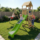 A wooden children's playset in a backyard with a bright green slide, climbing ladder, and swing set, with several children playing on the grass under a sunny sky.