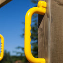 Close-up of yellow safety handles on a wooden structure with a blue sky and greenery in the background.